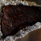 Smoked tri-tip resting in foil with a dark Ancho and Pasilla crust