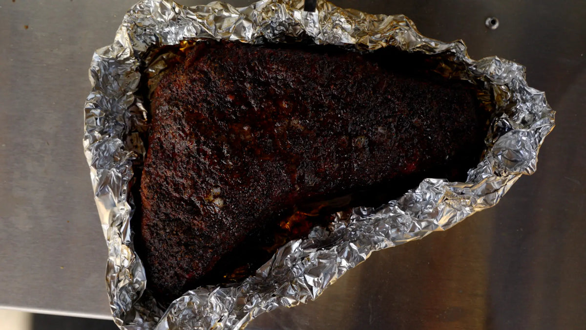 Smoked tri-tip resting in foil with a dark Ancho and Pasilla crust