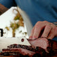Ty slicing smoked Trisket on a cutting board