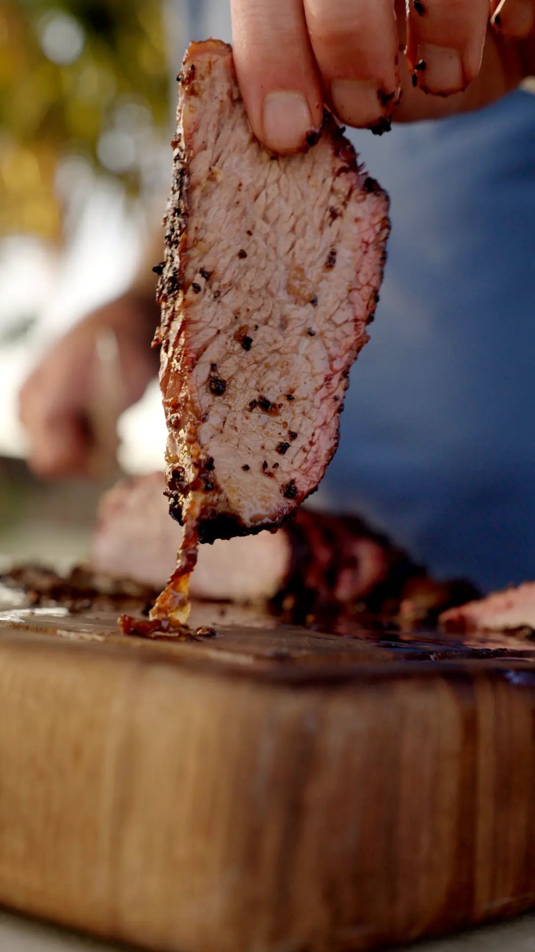 Hand holding a slice of smoked Trisket